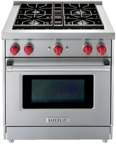 a silver stove top oven sitting on top of a white countertop with red knobs