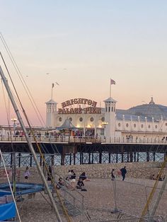 people are sitting on the beach next to boats and piers in front of a white building