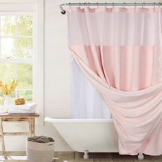 a bath tub sitting next to a window covered in a pink shower curtain over it