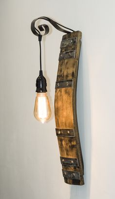 a light that is on the wall next to a wooden plank with a light bulb hanging from it