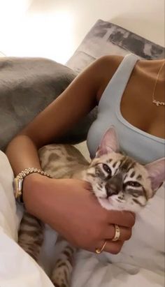 a woman is laying in bed with her cat and holding it up to her chest