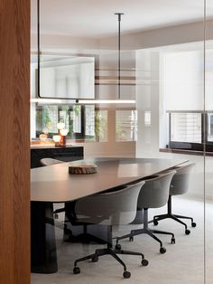 a conference table with four chairs in an office space that is open to the kitchen and dining area