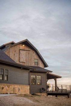 a large gray barn sitting on top of a dirt field