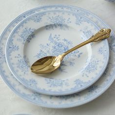 a gold spoon sitting on top of a white plate next to another blue and white plate