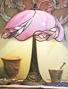 a pink lamp sitting on top of a table next to vases and other items