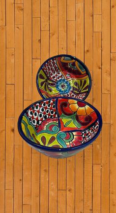 two colorful bowls sitting on top of a wooden floor