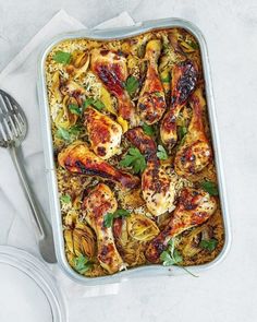 a pan filled with chicken and rice next to a fork