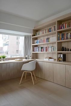 a chair sitting in front of a window next to a book shelf filled with books