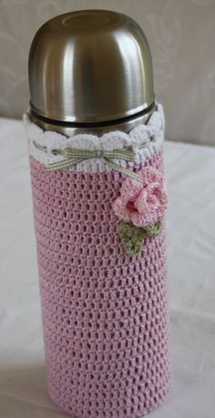 a pink crocheted can holder with a flower on the side and a metal lid