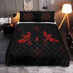 a bed covered in black and red comforter with two horses on it's side