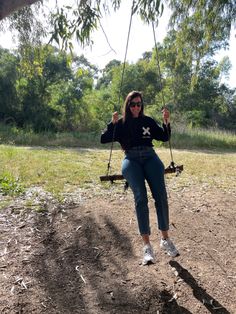 a woman sitting on a swing in the park