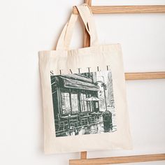 This canvas tote perfectly sized at 15" x 16" to compliment any #ootd. Great as a birthday gift for friends and family members for any occasion. ::DETAILS:: - 100% cotton canvas - 15" x 16" (38cm x 40cm) - 20" handles - Front side print only - Heavy fabric (12 oz/yd² (406.9 g/m - Sewn-in label - Please note the canvas is "natural/beige", not off-white ::IMPORTANT NOTICE:: - Cancellations or changes to personalized orders will not be accepted once your order has been placed. - Colors may vary depending on the screen/device, and final printed product may be influenced by factors such as printer settings, paper type, and environmental conditions. Each item is made to order. - Made to order in the USA. Actual shipment of items may vary depending on location and time of order placement. Standar Cafe Street, Restaurant Outdoor, Seattle Coffee, Seattle Restaurants, Air Art, Art Aesthetics, Outdoor Cafe, Friend Birthday Gifts, Canvas Tote Bag