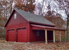 a red barn with two garages in the middle of trees and leaves on the ground