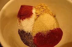 a white bowl filled with different colored powdered items on top of a wooden table