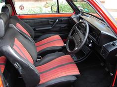 the interior of an old car with red and black stripes on it's seat covers