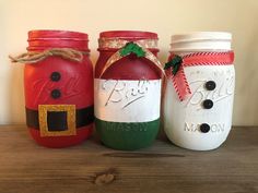 three mason jars decorated like santa claus and snowman faces, each painted different colors