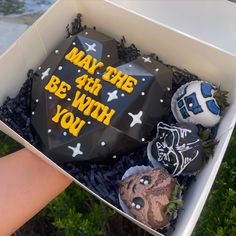 someone is holding a box with some cake in it that says may the 4th be with you