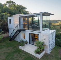 a house made out of shipping containers with stairs leading up to the roof and windows