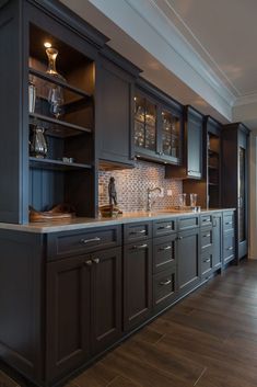 a kitchen with black cabinets and wooden floors