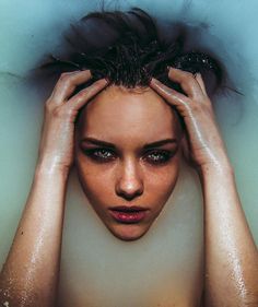 a woman in a bathtub with her hands on her head