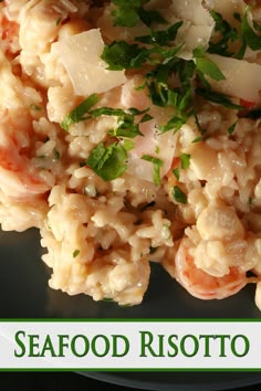 seafood risotto on a black plate with parsley garnish and herbs