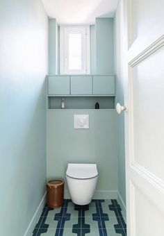 a white toilet sitting inside of a bathroom next to a window on top of a tiled floor