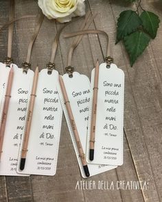 three small tags with writing on them next to a rose and two pens in it