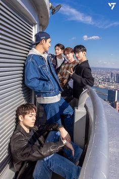 four young men standing on the edge of a building looking at something in front of them