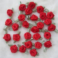 red roses with green leaves are arranged on a white surface