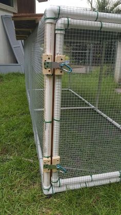 a white fence with green wire around it on the grass near a house and yard