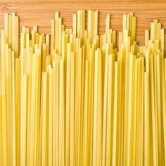 yellow pasta sticks lined up on a wooden surface