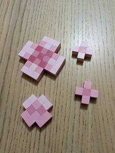 four pieces of pink paper are placed on a wooden surface with one piece cut out