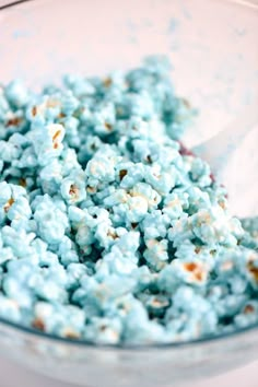 a bowl filled with blue popcorn sitting on top of a table