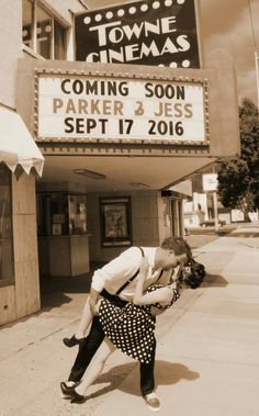 a man and woman kissing in front of a movie theater