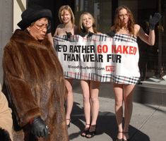 a group of women standing on the sidewalk holding up a sign that says, i'd rather go naked than we're fur