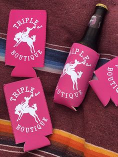 four pink bottle holders with white horse and rider on them, sitting next to a striped towel