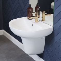 a white sink sitting next to a mirror in a bathroom under a faucet