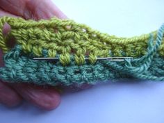 a hand holding a green crocheted piece of yarn