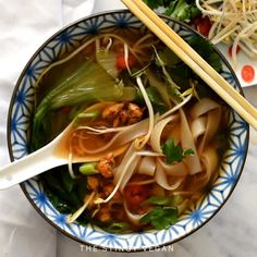 a bowl filled with noodles and vegetables next to chopsticks