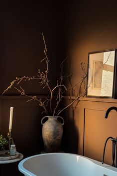 a vase with branches in it sitting next to a bathtub