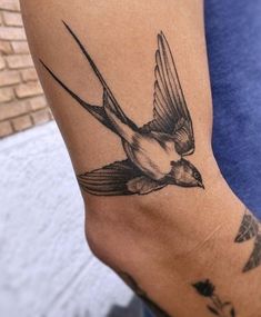 a small bird tattoo on the right arm