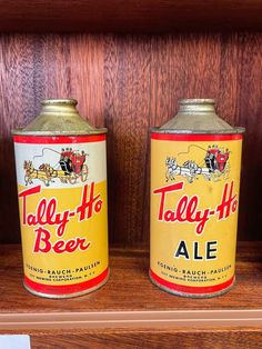 two beer cans sitting on top of a wooden shelf