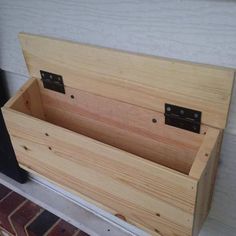 a wooden box sitting on top of a brick floor next to a window sill