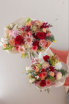 two bouquets of flowers sitting on top of each other in front of a white wall