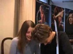 two women sitting next to each other in front of a movie poster on the wall