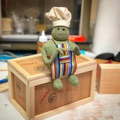 a stuffed animal sitting on top of a wooden box with a chef's hat