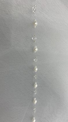 a close up of a necklace with pearls and beads hanging from it's side