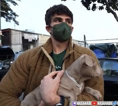 a man wearing a face mask holding a puppy