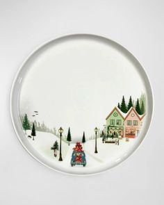 a plate with a painting of a car driving down the road in front of houses