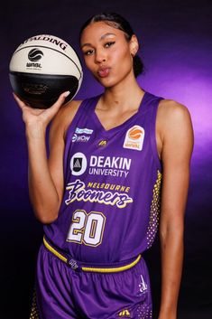 a woman holding a basketball in her hand and posing for a photo with the ball